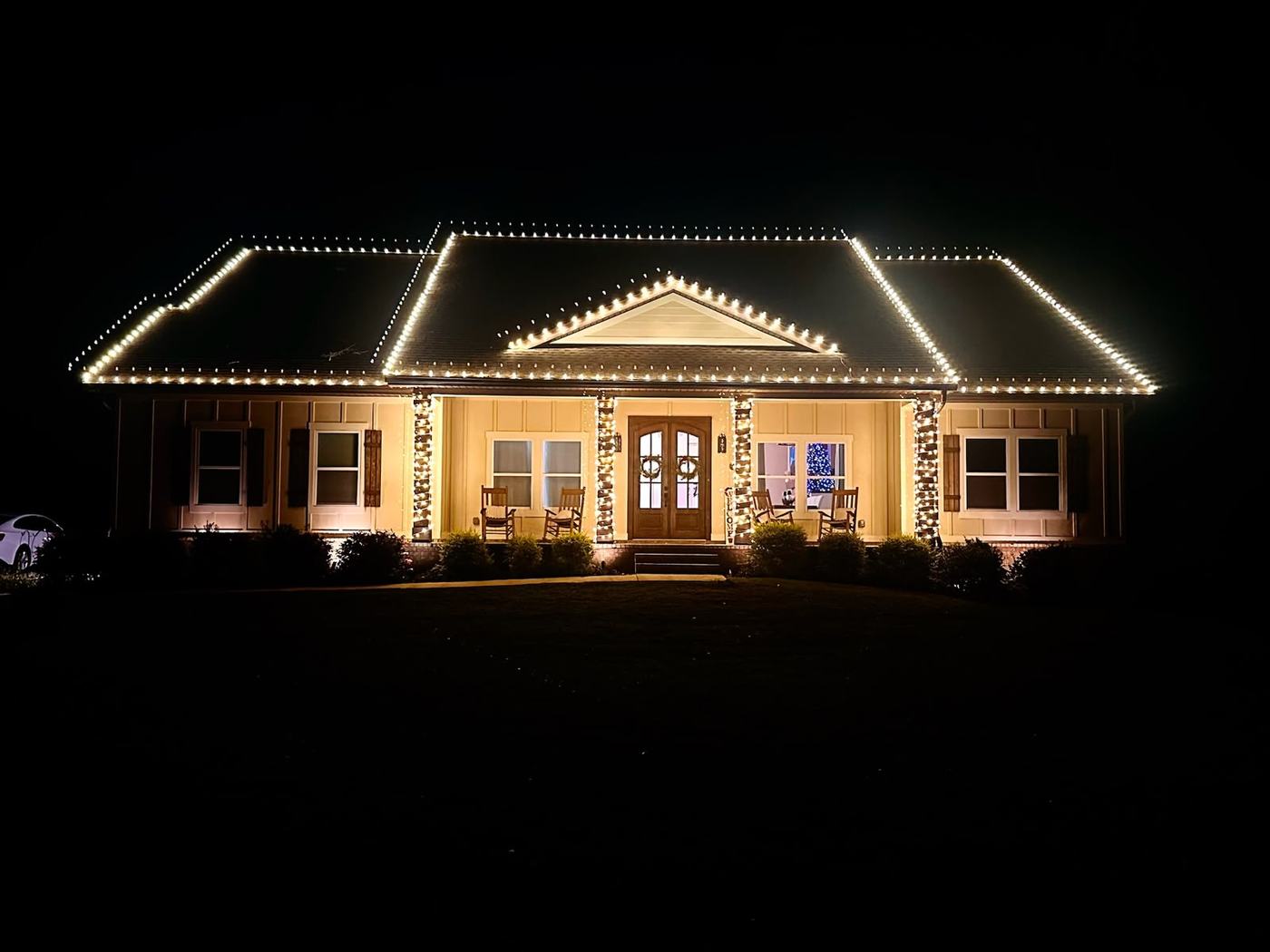 Warm white roofline and porch column lighting on a single-story Houston home
