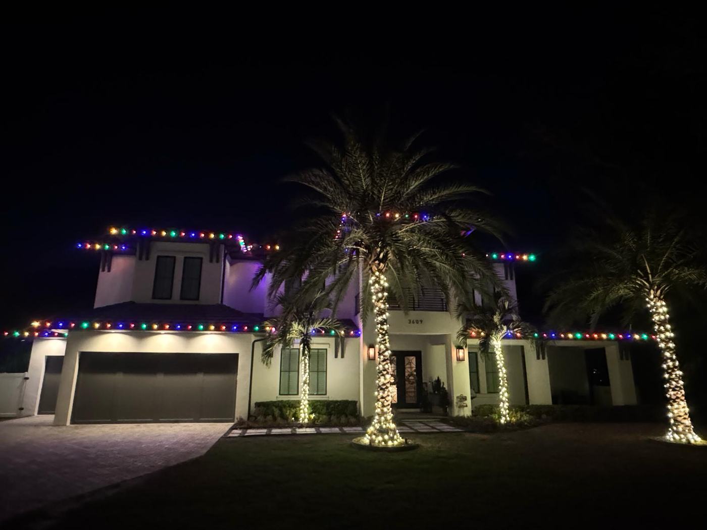 Multicolour roofline with warm white wrapped trees on a Houston home